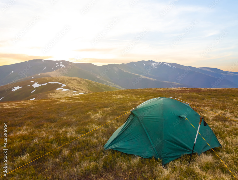 green touristic tent stay on mountain plateau at the sunset, travel outdoor background