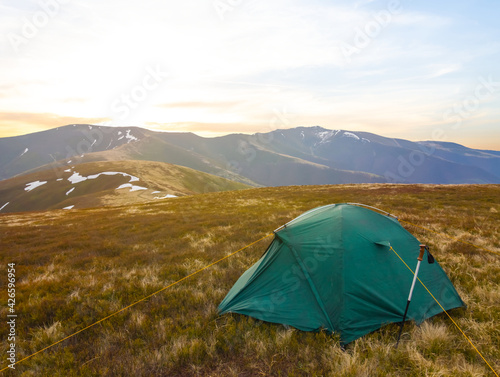 green touristic tent stay on mountain plateau at the sunset, travel outdoor background