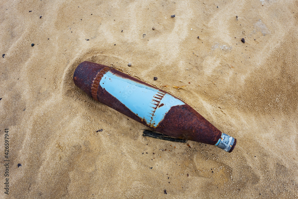 closeup old rusty bomb lie on sand, military firing background closeup old rusty bomb lie on sand, military firing background