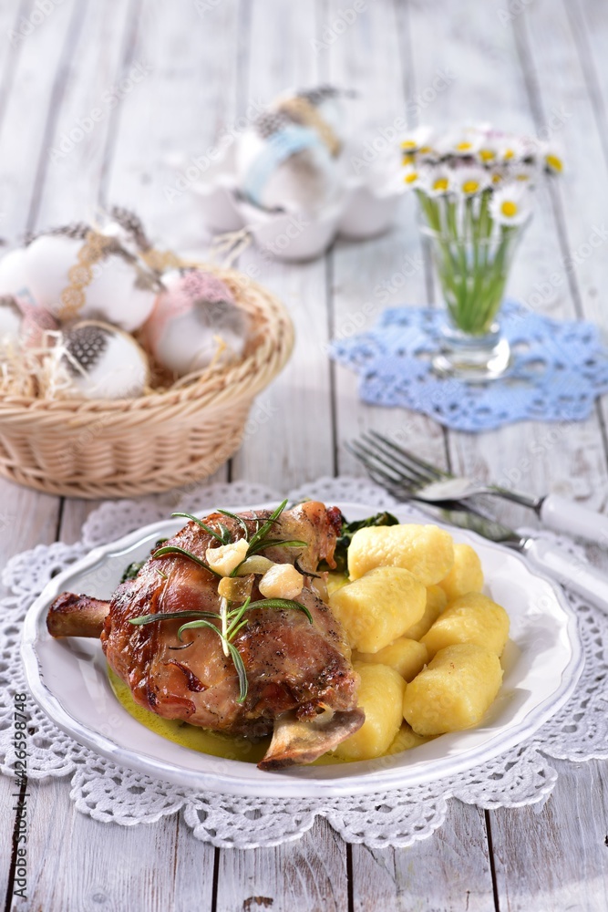 Leg of lamb with spinach and potato dumplings in spring with daisy flowers in the background Leg of lamb with spinach and potato dumplings in spring with daisy flowers in the background