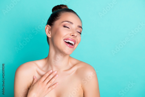 Photo of young happy excited smiling woman laughing apply moisturizing cream on body isolated on turquoise color background