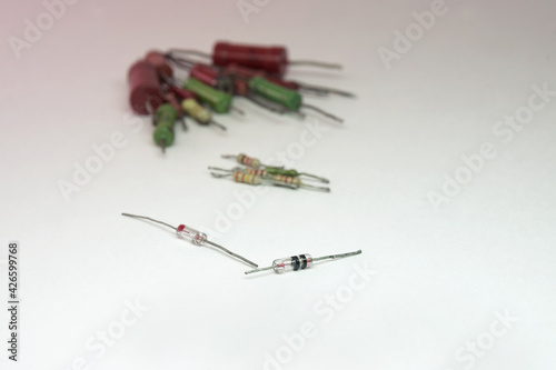 germanium rectifier diode in glass case with red dot on end and zener diode in transparent case with two black stripes. on blurry background, modern and vintage resistors photo