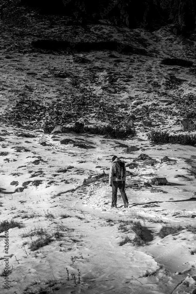 Black and white capture of a man hiking in the snowy mountains. Cold weather in Tatras National Park, Poland. Selective focus on the person, blurred background. Black and white capture of a man hiking in the snowy mountains. Cold weather in Tatras National Park, Poland. Selective focus on the person, blurred background.