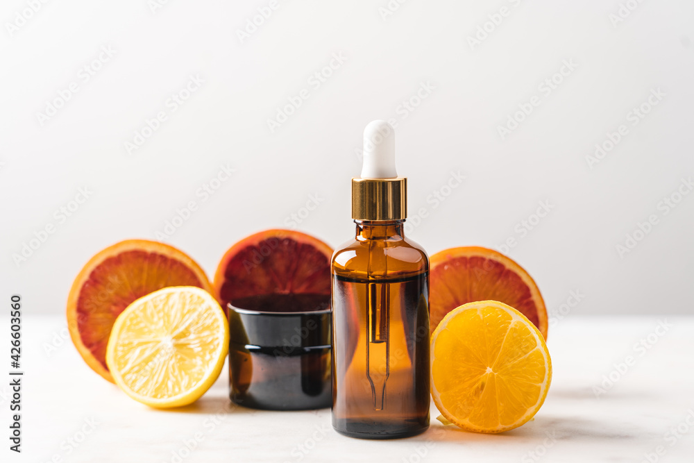 Serum in glass bottle with pipette on the background of slices of orange and lemon. Cosmetic product in bottle with vitamin C Serum in glass bottle with pipette on the background of slices of orange and lemon. Cosmetic product in bottle with vitamin C