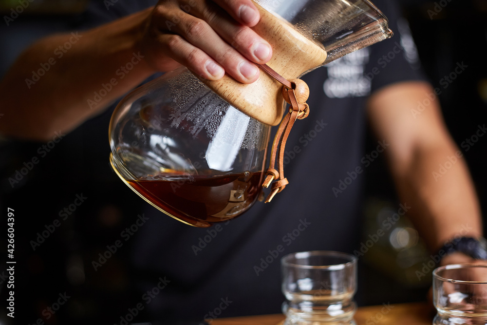 Barista preparing coffee using chemex pour over coffee maker. Alternative ways of brewing coffee. Coffee shop concept.
