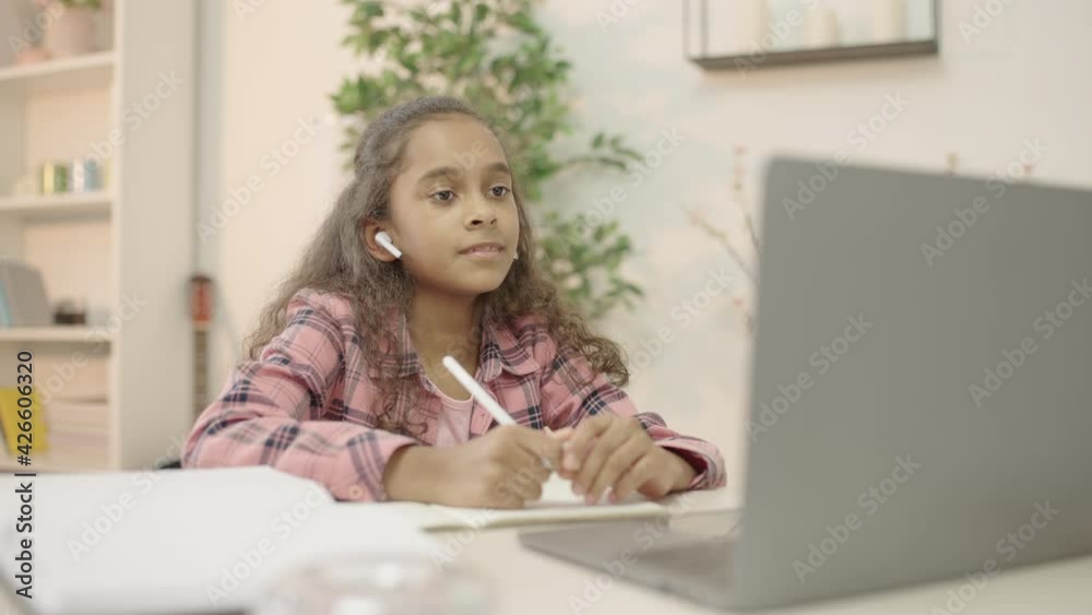 Biracial girl making video call on laptop, talking to teacher online, studying Biracial girl making video call on laptop, talking to teacher online, studying