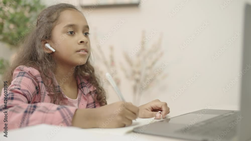 Schoolgirl having online lesson, making video call on laptop, home education Schoolgirl having online lesson, making video call on laptop, home education