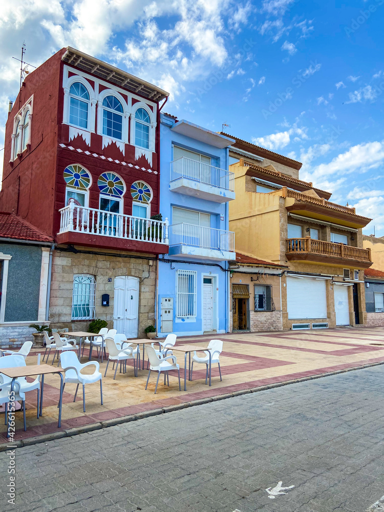 Curious colorful houses with a restaurant terrace at the base next to the beach of Alicante, Spain.
