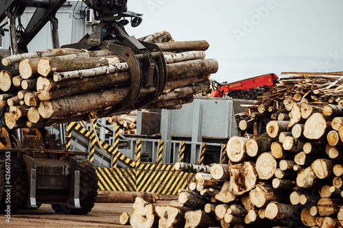 the front loader works in a wood processing plant. industrial excavator with mechanical gripper transports wood in the warehouse
