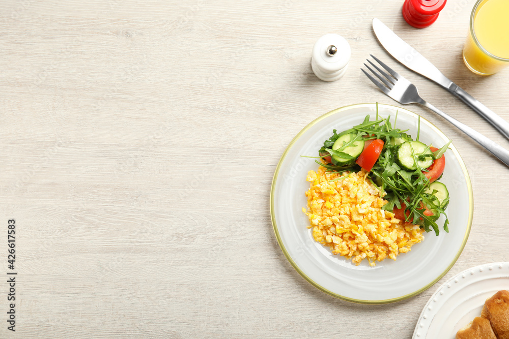 Tasty scrambled eggs with garnish served on white wooden table, flat lay. Space for text Tasty scrambled eggs with garnish served on white wooden table, flat lay. Space for text