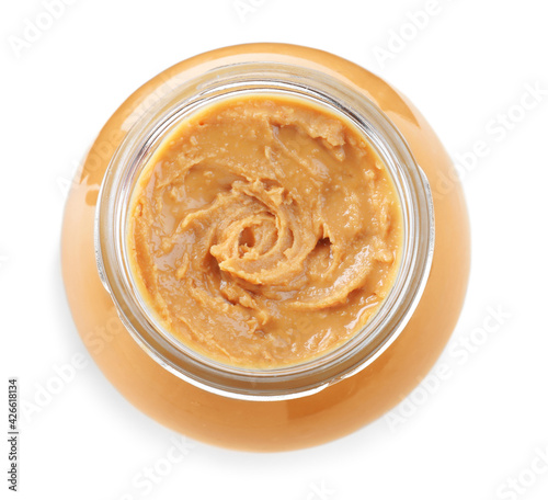 Delicious peanut butter in glass jar isolated on white, top view