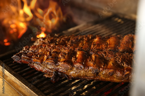 Grilling grate with tasty pork ribs in oven, closeup