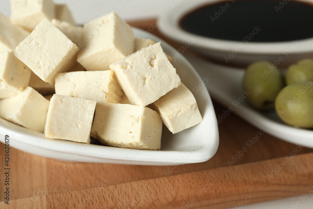 Pieces of delicious tofu and olives on wooden board, closeup. Soybean curd Pieces of delicious tofu and olives on wooden board, closeup. Soybean curd