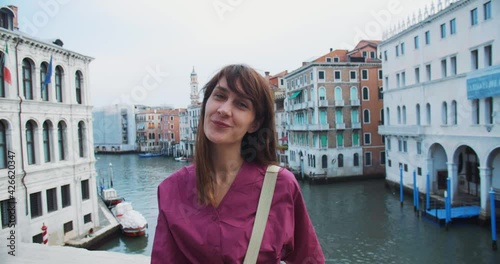Portrait of happy beautiful dark haired female tourist blowing air kiss at camera enjoying summer Venice vacation trip.