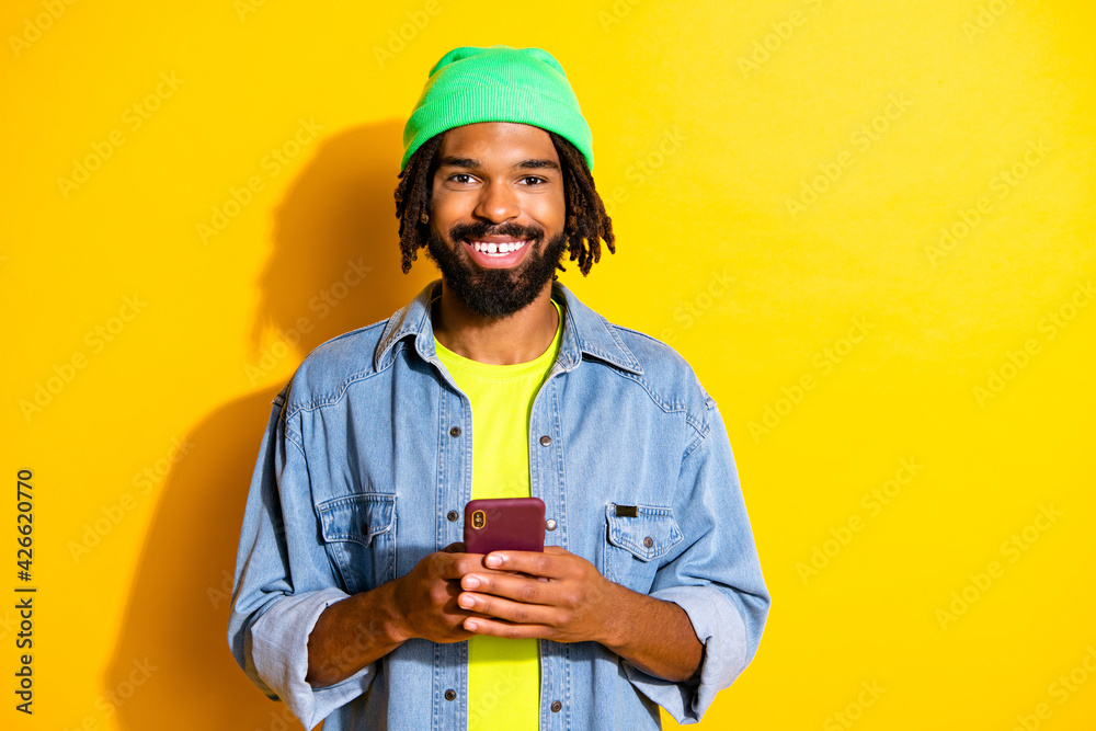 Photo of young positive cheerful smiling african blogger man using smartphone isolated on yellow color background