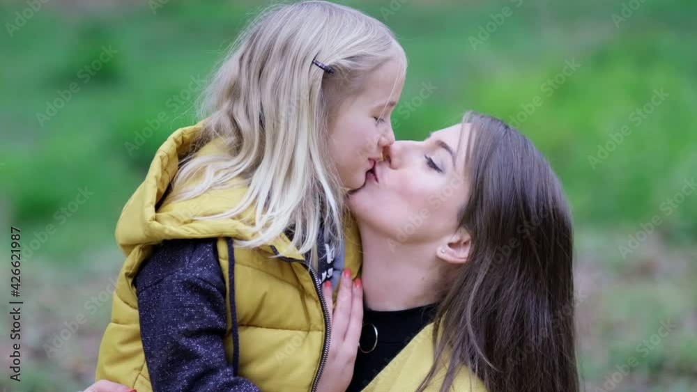 Kissing and hugging happy family. Beautiful Mother And her little daughter outdoors. Nature. Beauty Mum and her Child playing in Park together. video stock footage. Slow motion soft focus Kissing and hugging happy family. Beautiful Mother And her little daughter outdoors. Nature. Beauty Mum and her Child playing in Park together. video stock footage. Slow motion soft focus