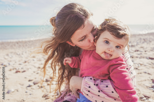 Happy family moment of a young mom enjoying a day on the beach with her baby © nanihta