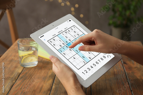Woman playing sudoku game on tablet indoors, closeup