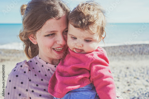 Happy family moment of a young mom enjoying a day on the beach with her baby