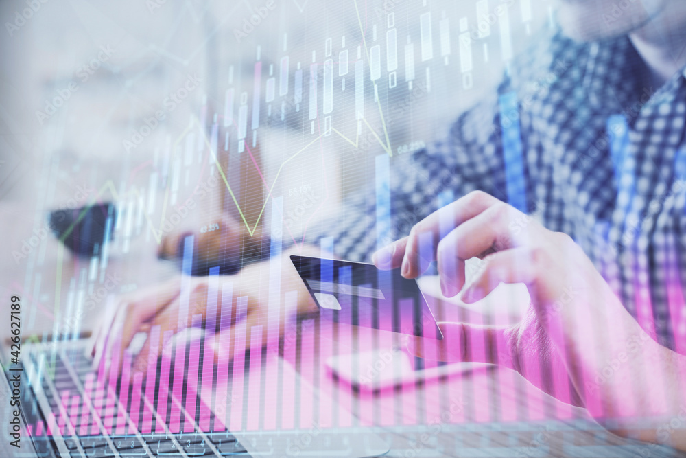 Double exposure of man hands holding a credit card and Forex graph drawing. Stock trading and digital fintech in Internet E-commerce concept.