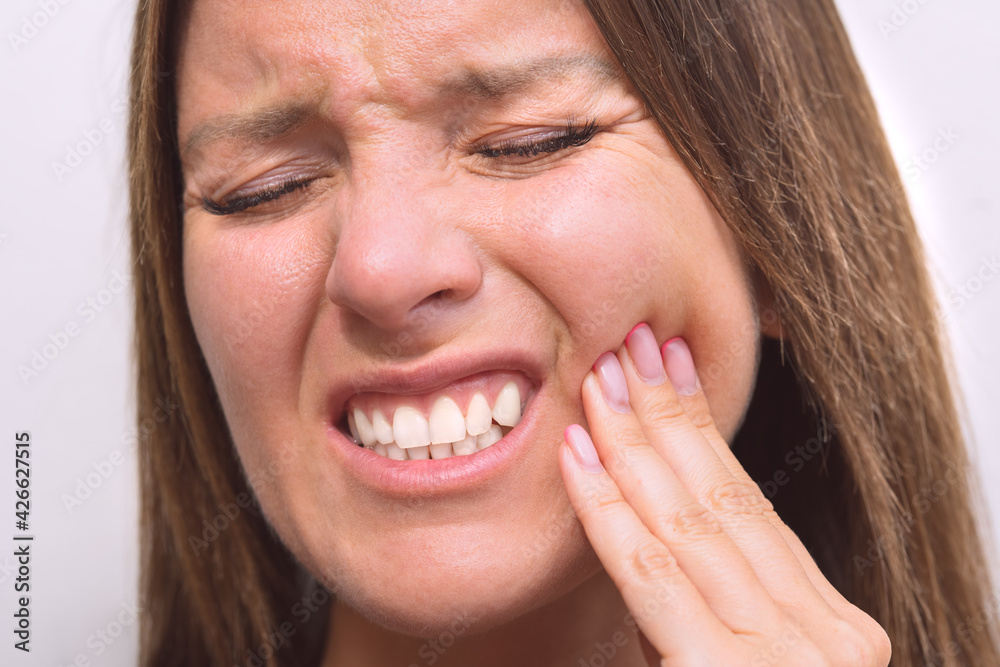 Woman touching her cheek because of tooth pain. Woman suffering from toothache, dental illness or oral diseases. Closeup of woman face with painful expression. Teeth problem. Female feeling tooth pain Woman touching her cheek because of tooth pain. Woman suffering from toothache, dental illness or oral diseases. Closeup of woman face with painful expression. Teeth problem. Female feeling tooth pain