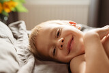 A boy smiling and playing in bed.