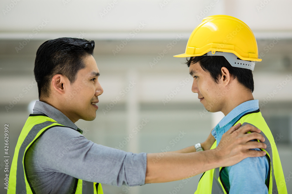 Senior and junior engineers talking together with intimated manner. Concept for good teamwork and unity of colleauges. Senior and junior engineers talking together with intimated manner. Concept for good teamwork and unity of colleauges.
