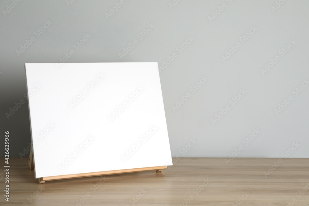 Wooden easel with blank canvas on table. Space for text Wooden easel with blank canvas on table. Space for text