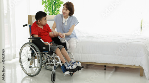 Smiling young Asian doctor massaging hand of little ethnic patient with disability