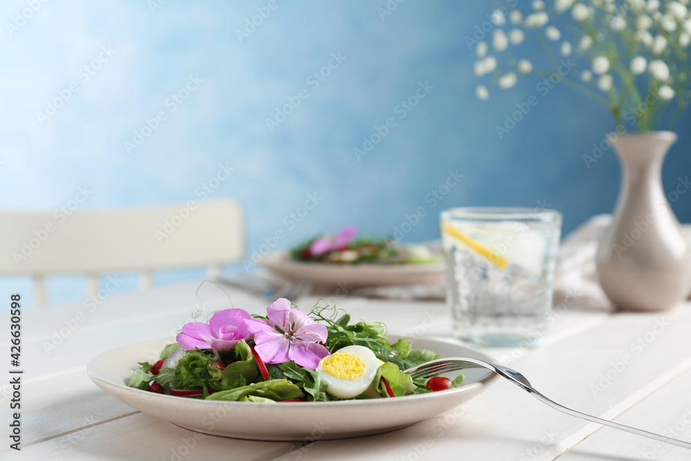 Fresh spring salad with flowers served on white wooden table Fresh spring salad with flowers served on white wooden table