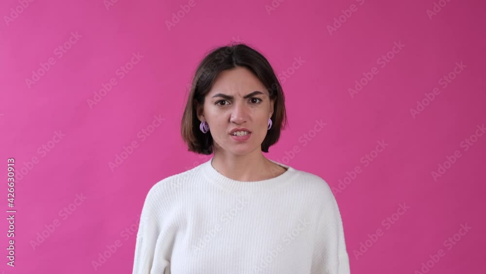 Woman in casual white sweater and hat on pink background isolated angry look to camera screaming Woman in casual white sweater and hat on pink background isolated angry look to camera screaming
