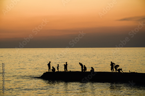 Sunset on the Black Sea. Silhouettes of fishermen on the pier.