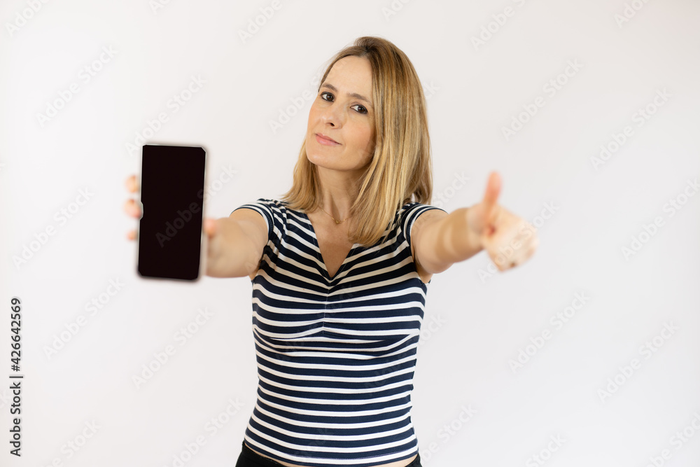 Portrait of a beautiful young woman wearing striped t-shirt with thumb up showing mobile phone isolated over white background Portrait of a beautiful young woman wearing striped t-shirt with thumb up showing mobile phone isolated over white background