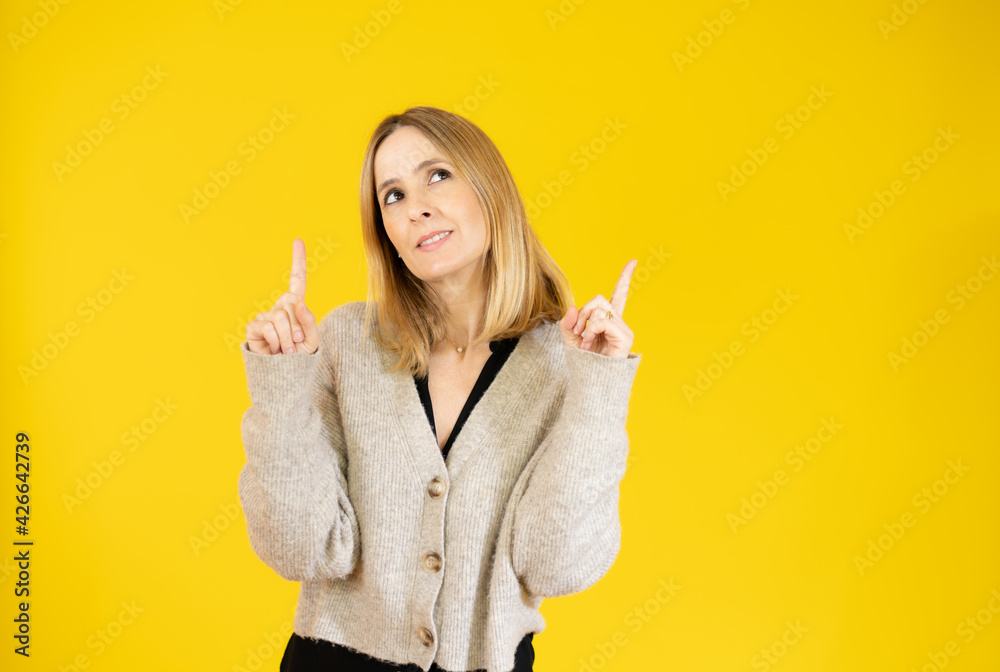 Portrait of beautiful young woman pointing up over yellow background. Portrait of beautiful young woman pointing up over yellow background.