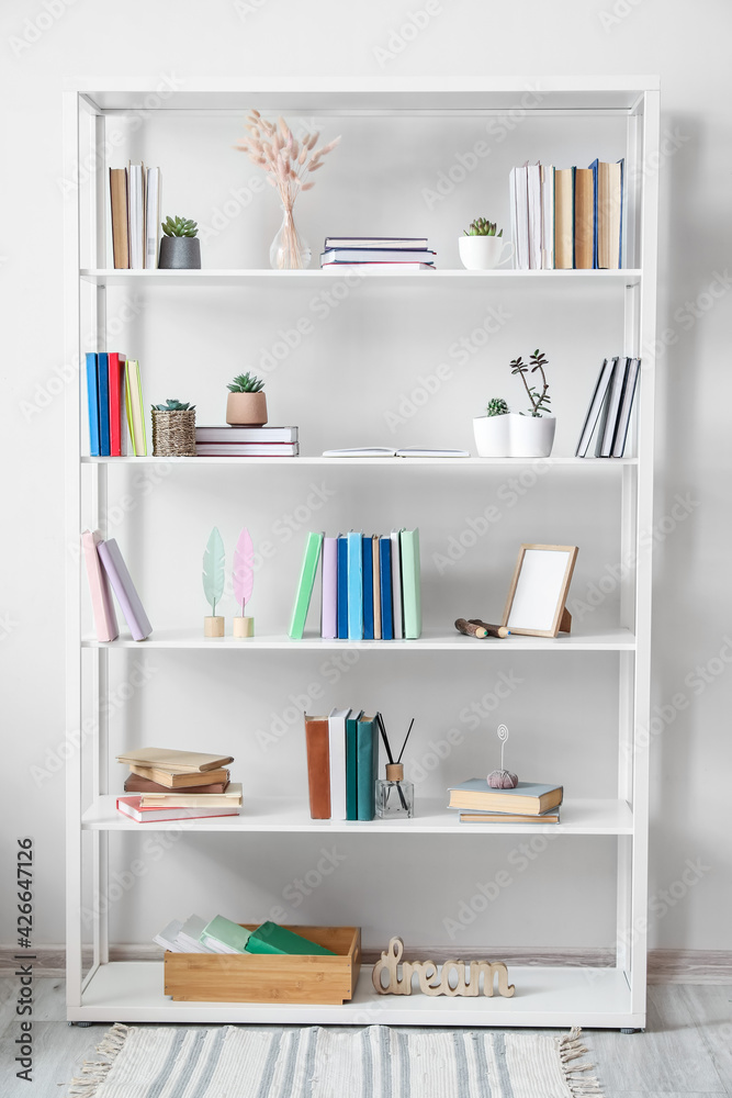 Shelf unit with books and decor near light wall Shelf unit with books and decor near light wall