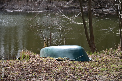 Umgedrehtes grünes Boot liegt an Land an einem See photo