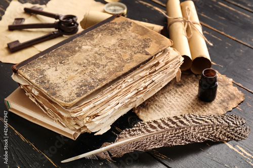 Photography Old book, feather, compass, scrolls and keys on dark wooden background