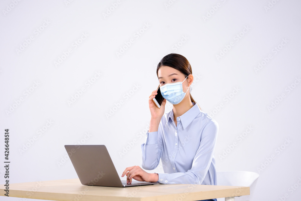 A young lady with a mask is on the phone in the office A young lady with a mask is on the phone in the office
