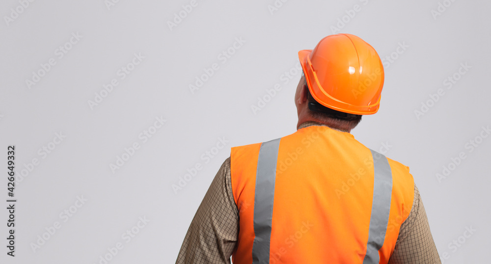 back of contruction worker in hard hat and reflective vest on grey studio background looking, successful business, place for advertising back of contruction worker in hard hat and reflective vest on grey studio background looking, successful business, place for advertising