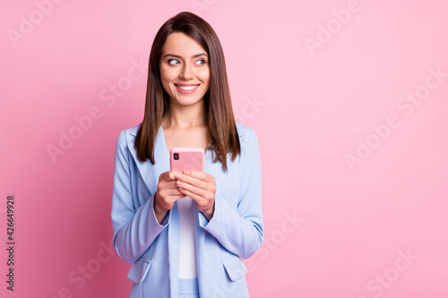 Photo of young beautiful girl use smartphone chat type dream look empty space isolated over pink color background