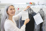 Happy woman near clothes rack in dry cleaning