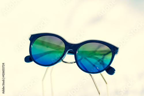Fashion cat eye sunglasses model for ladies with big round colored lenses and black frame shoot outside in a sunny day closeup. Selective focus . High quality photo © Cariman