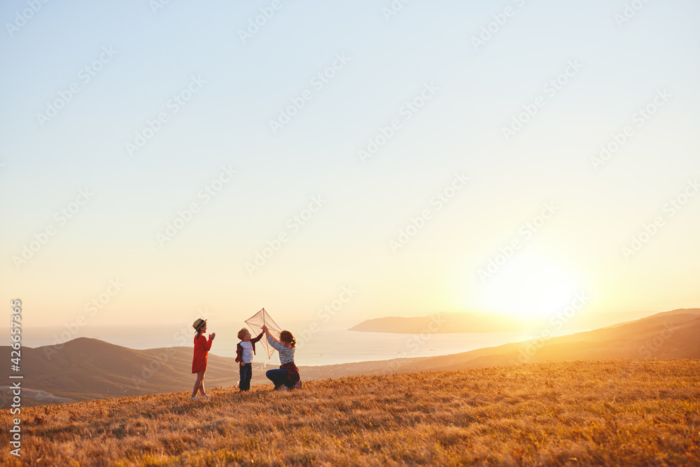 Happy family  mother and kids  launch  kite on nature at sunset