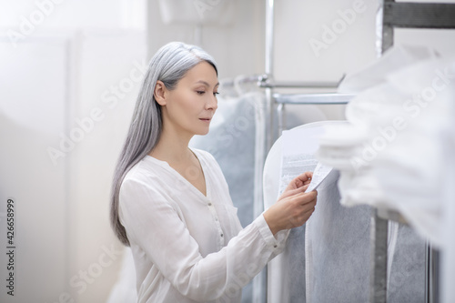 Adult pretty woman studying information on clothing tag
