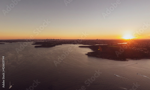 Aerial high angle drone sunset view of the Sydney Harbour area, New South Wales, Australia, with the CBD area with the Harbour Bridge and North Sydney on the left and Chatswood below the sun.
