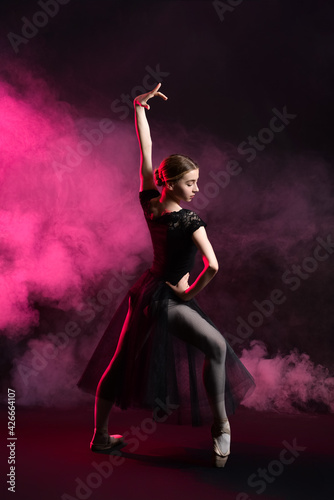 Beautiful young ballerina on dark color background