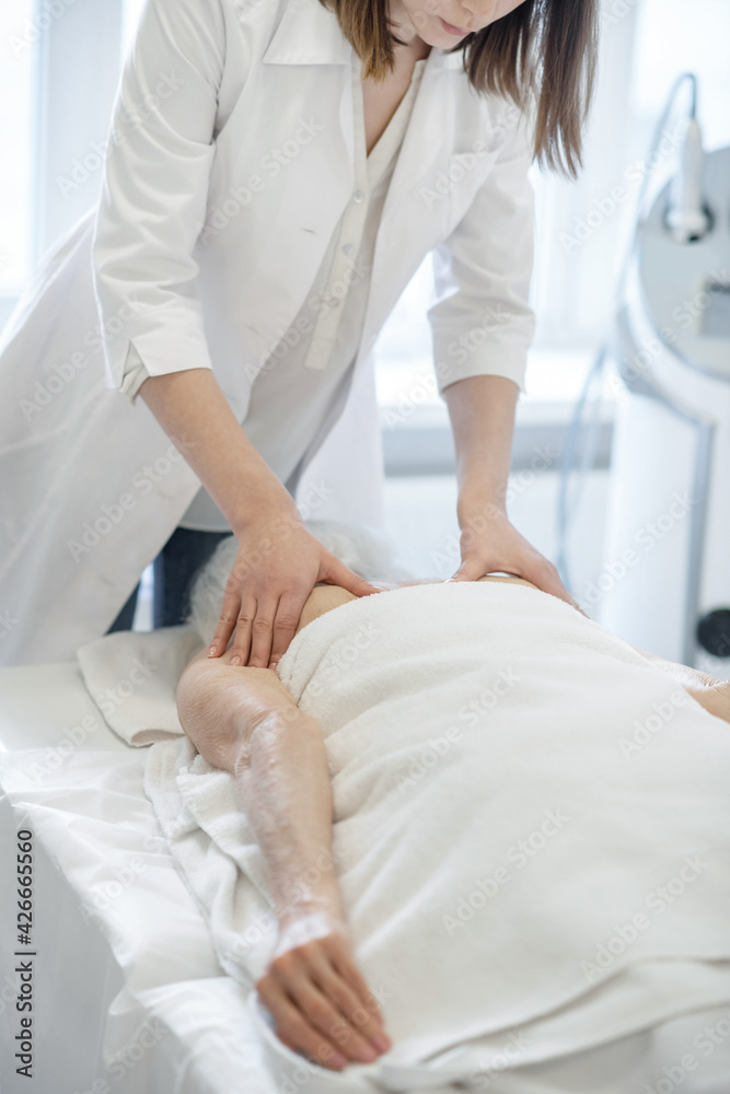 Female massage therapist doing back massage procedures to a woman