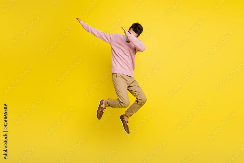 Full body photo fo young man jump up cover face hands dance active isolated over yellow color background