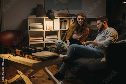 romantic young couple listening to a music on record player at home