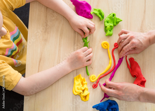 Child hands playing with colorful clay. Homemade plastiline. Activities for children in quarantine. Girl sculpts from plasticine at home on isolation. Coronavirus 2021.